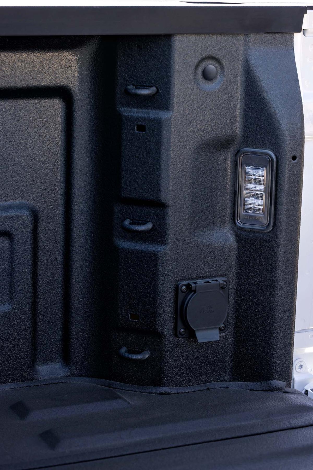 Spray-in bed liner wall on a 2027 GMC Sierra 1500 with LED cargo lamp, power outlet, and tie-down loops