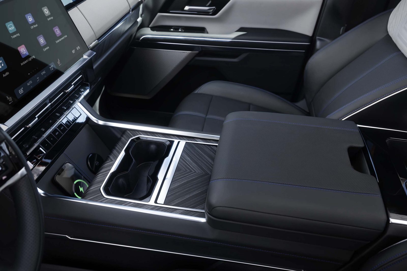 2027 GMC Sierra 1500 center console with wireless phone charging pad, cupholders, and padded armrest