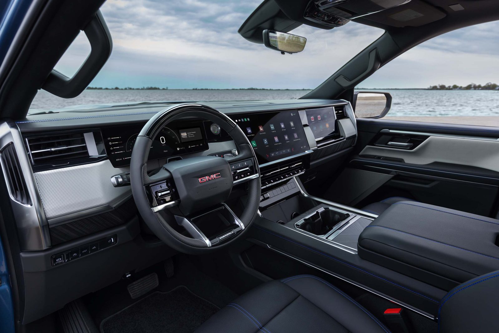 2027 GMC Sierra 1500 Denali interior with blue contrast stitching, Denali steering wheel, and 16.3-inch touchscreen