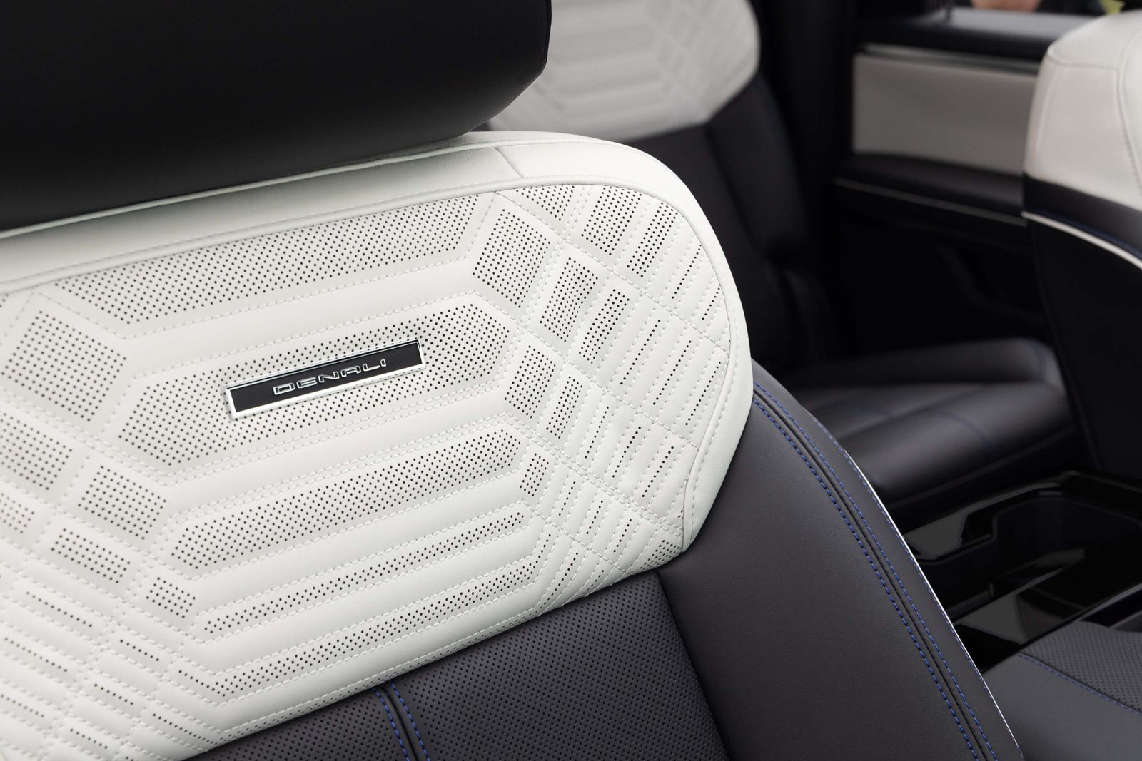 Close-up of a white perforated leather 2027 GMC Sierra 1500 Denali front seat with Denali badge