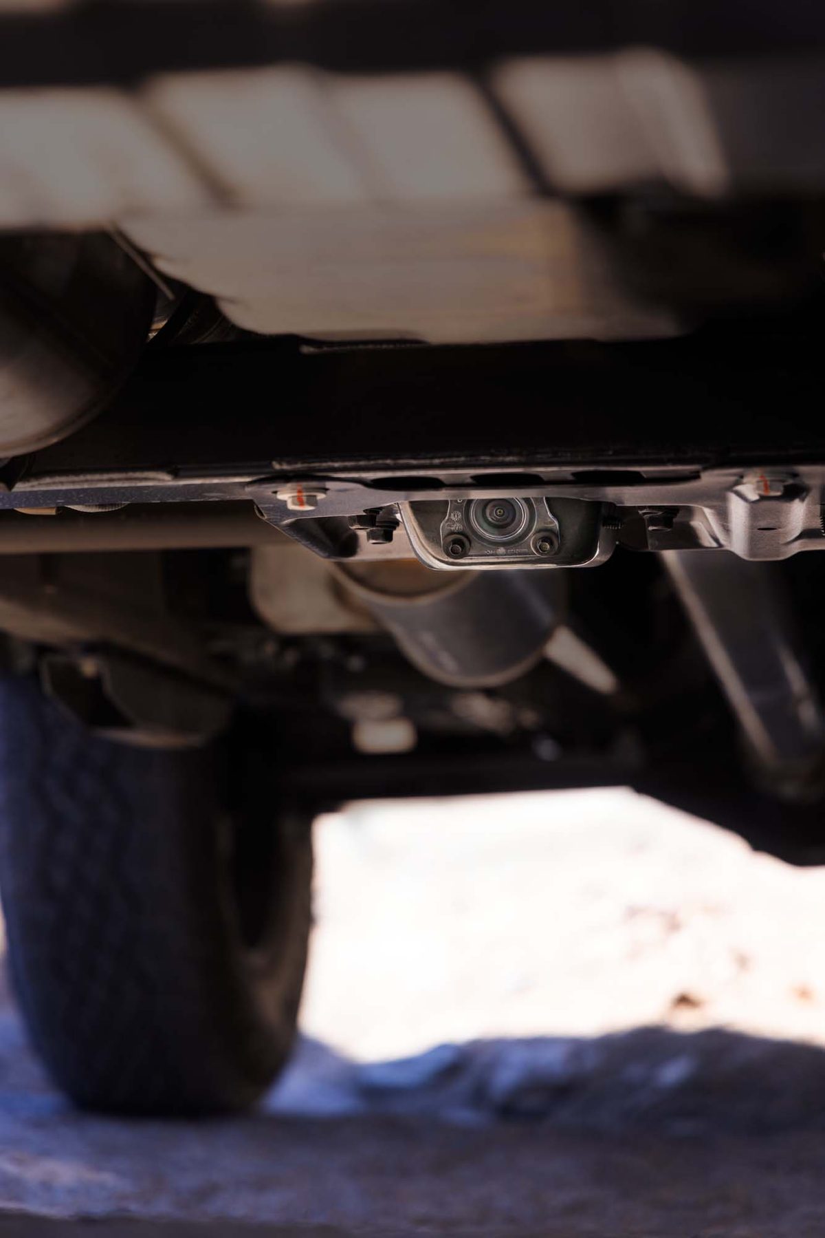 Underbody camera mounted beneath a 2027 GMC Sierra 1500, seen from ground level